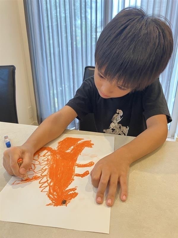 恐竜の絵に集中してお絵描きを楽しんでいるお子さん